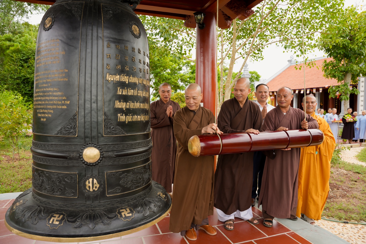 A group of people standing around a large bell Description automatically generated