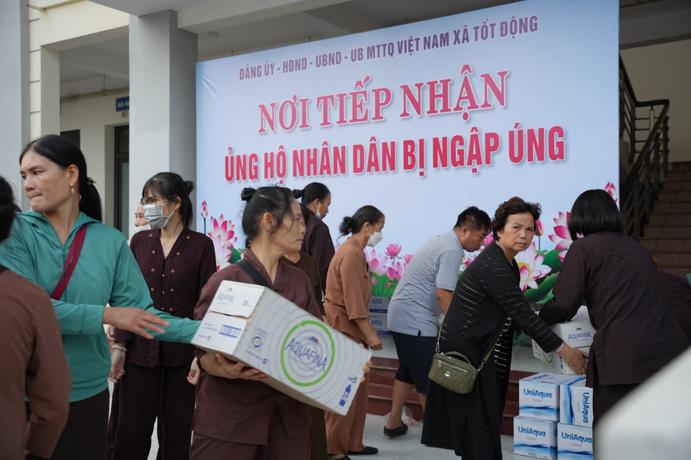 A group of people standing in front of a sign Description automatically generated