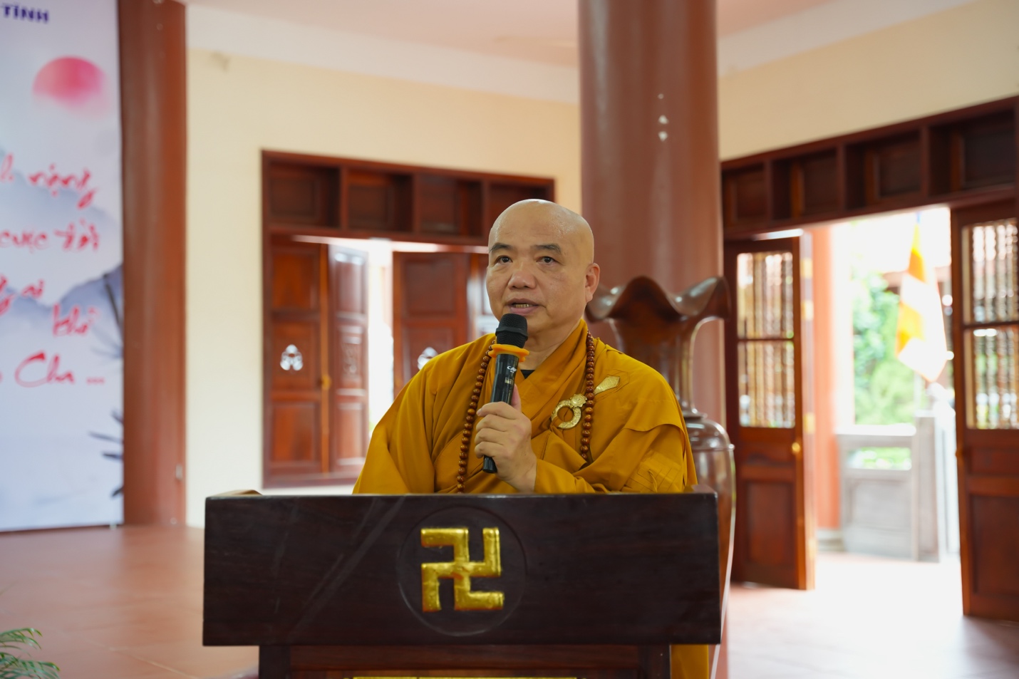 A person in a yellow robe holding a microphone Description automatically generated