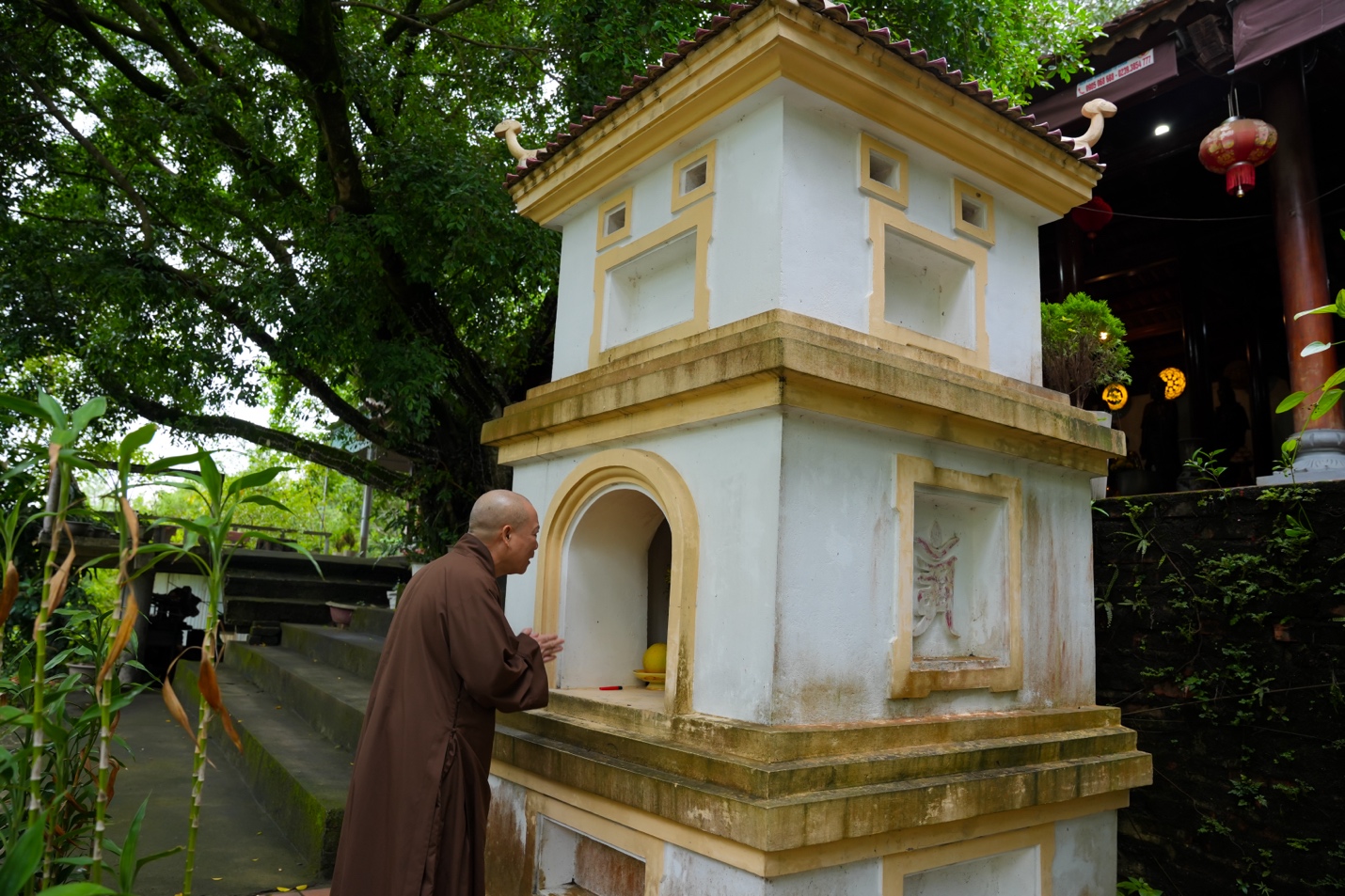 A person standing next to a small shrine Description automatically generated