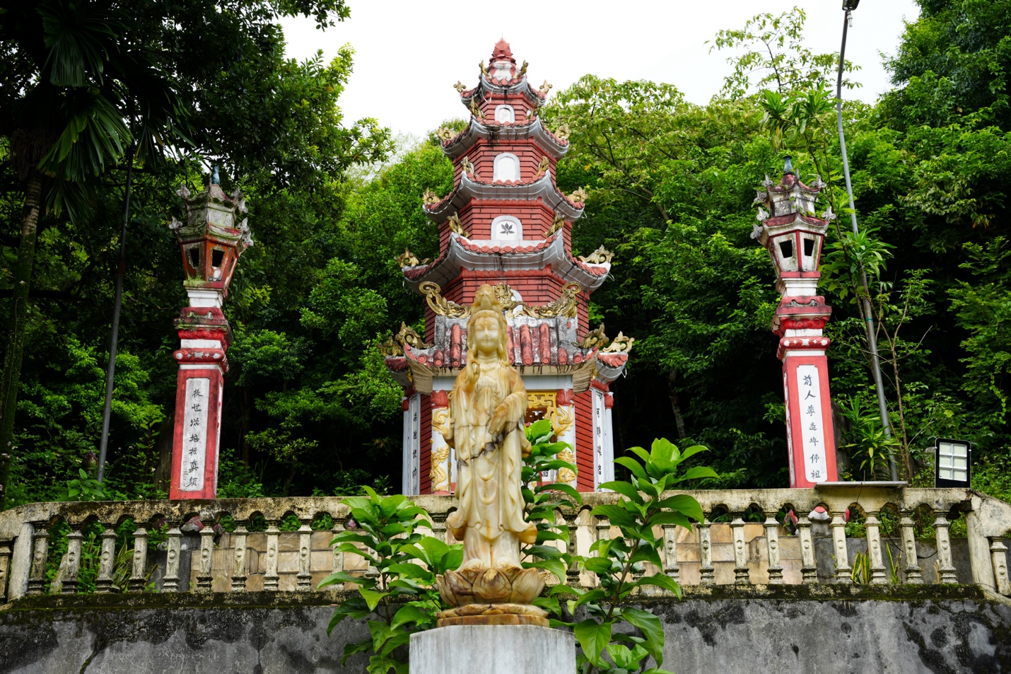 A statue in front of a red pagoda Description automatically generated