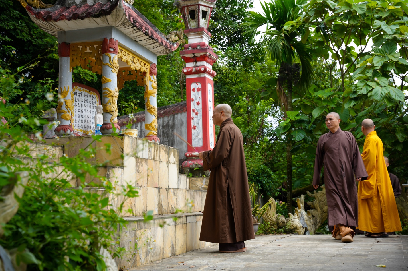 Two men in robes walking in a garden Description automatically generated