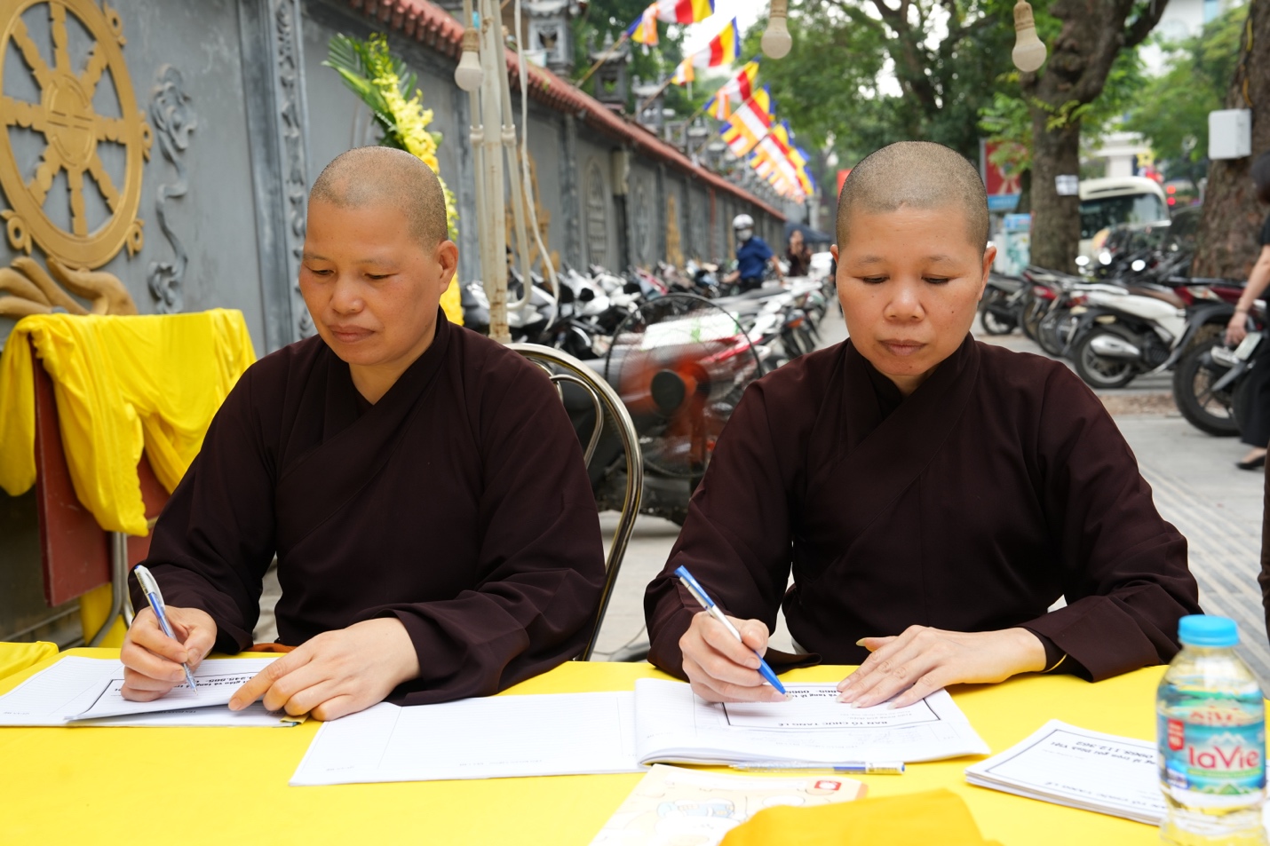 A couple of monks sitting at a table Description automatically generated