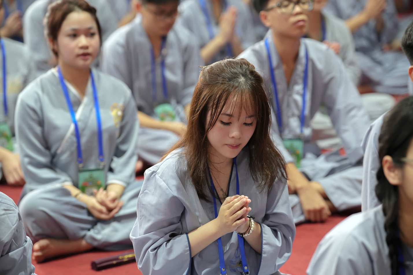 A group of people in grey robes praying AI-generated content may be incorrect.