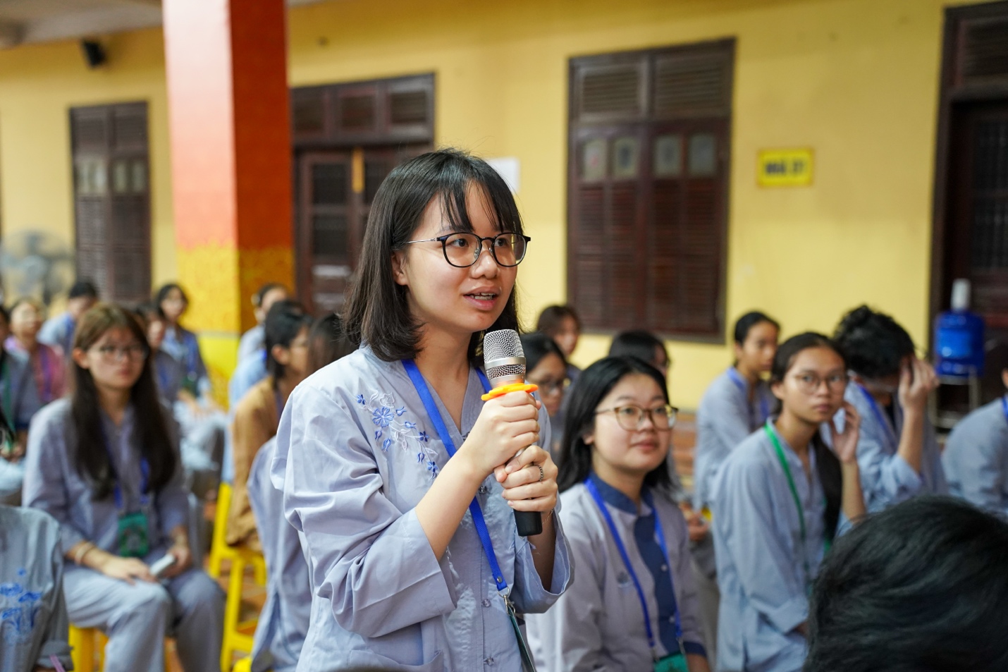 A person holding a microphone in front of a group of people AI-generated content may be incorrect.