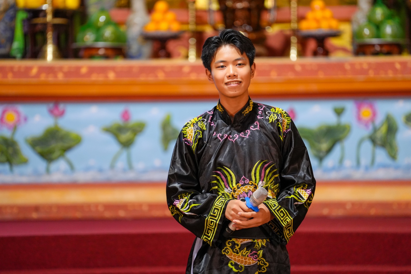 A person in a black robe holding a microphone AI-generated content may be incorrect.