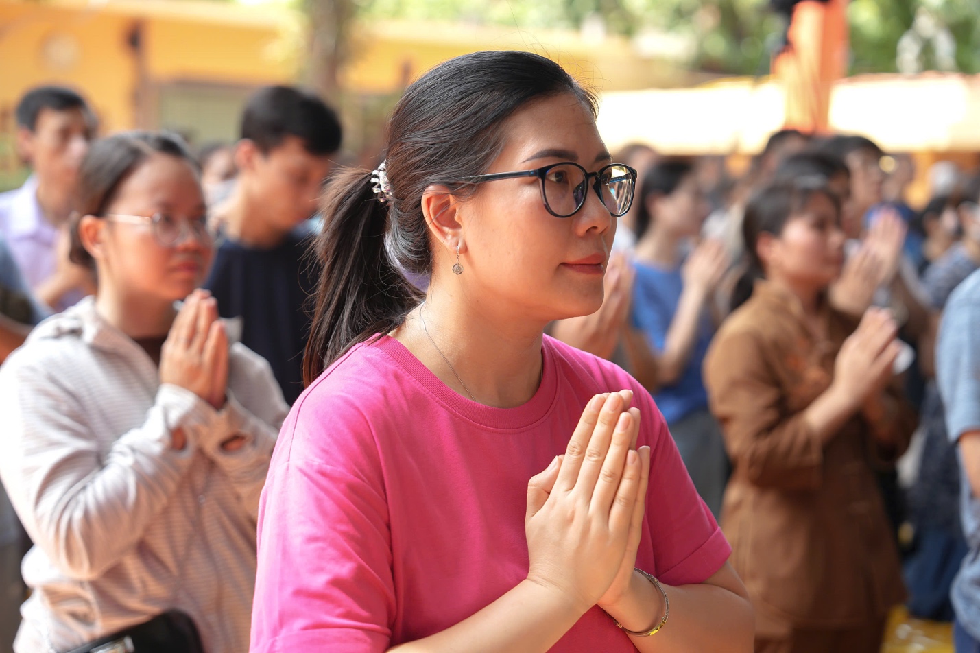 A person in a pink shirt with her hands together AI-generated content may be incorrect.