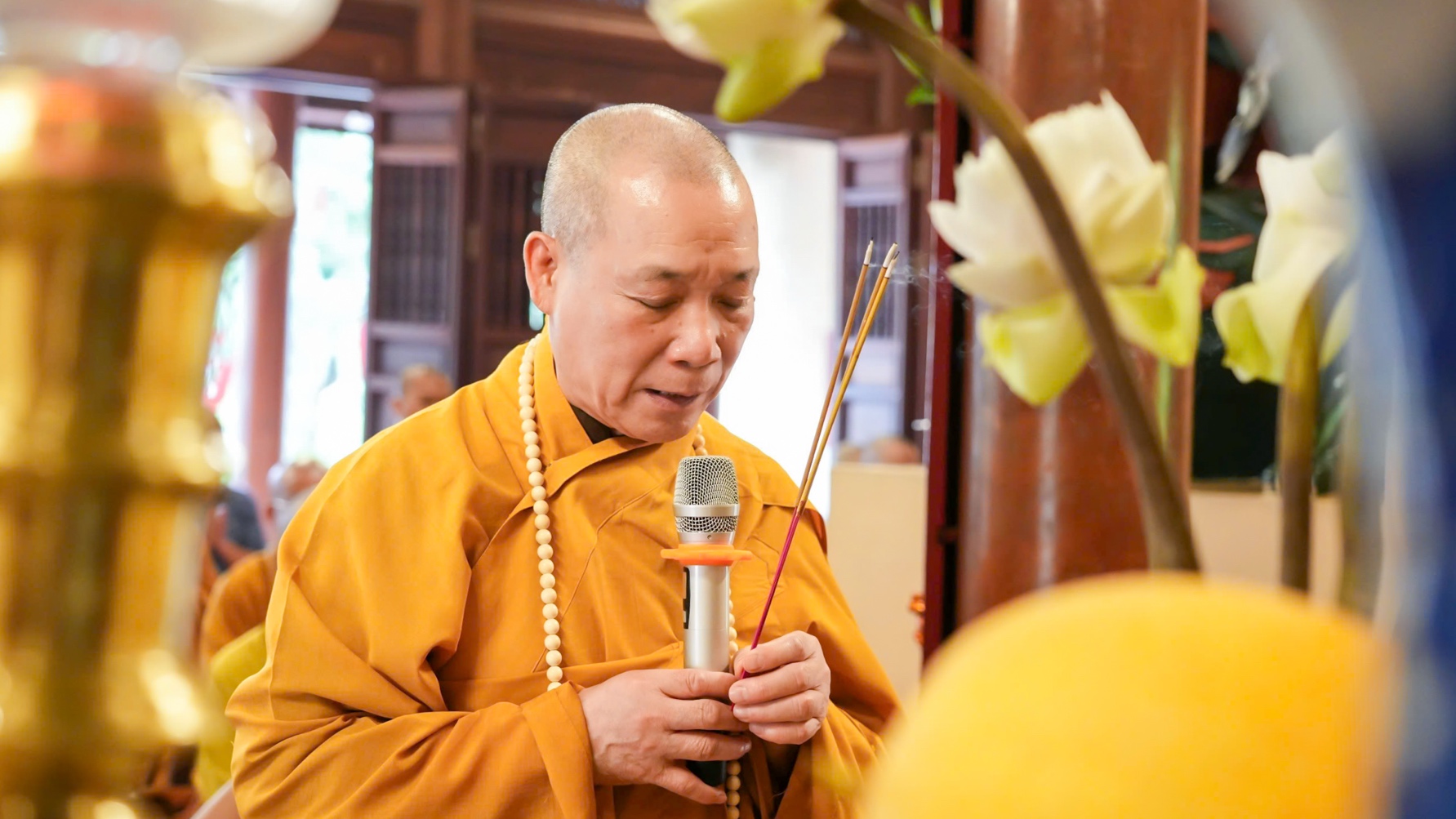 A person in a yellow robe holding a microphone AI-generated content may be incorrect.