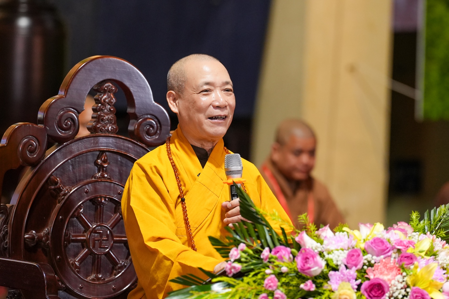 A person in a yellow robe holding a microphone AI-generated content may be incorrect.