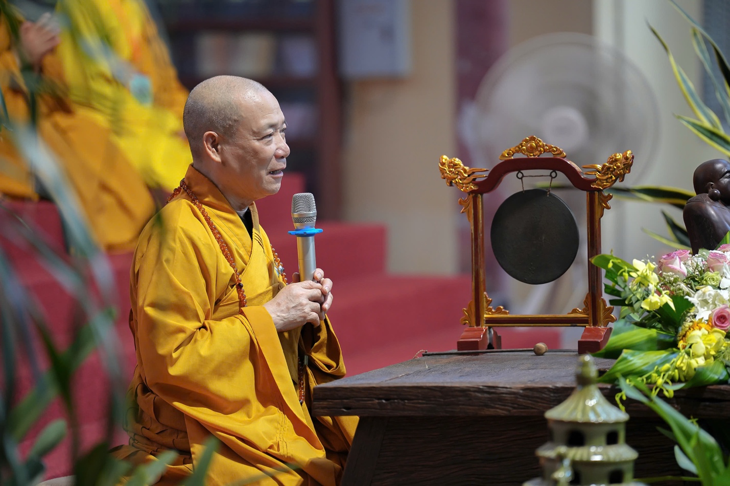A person in a yellow robe holding a microphone AI-generated content may be incorrect.