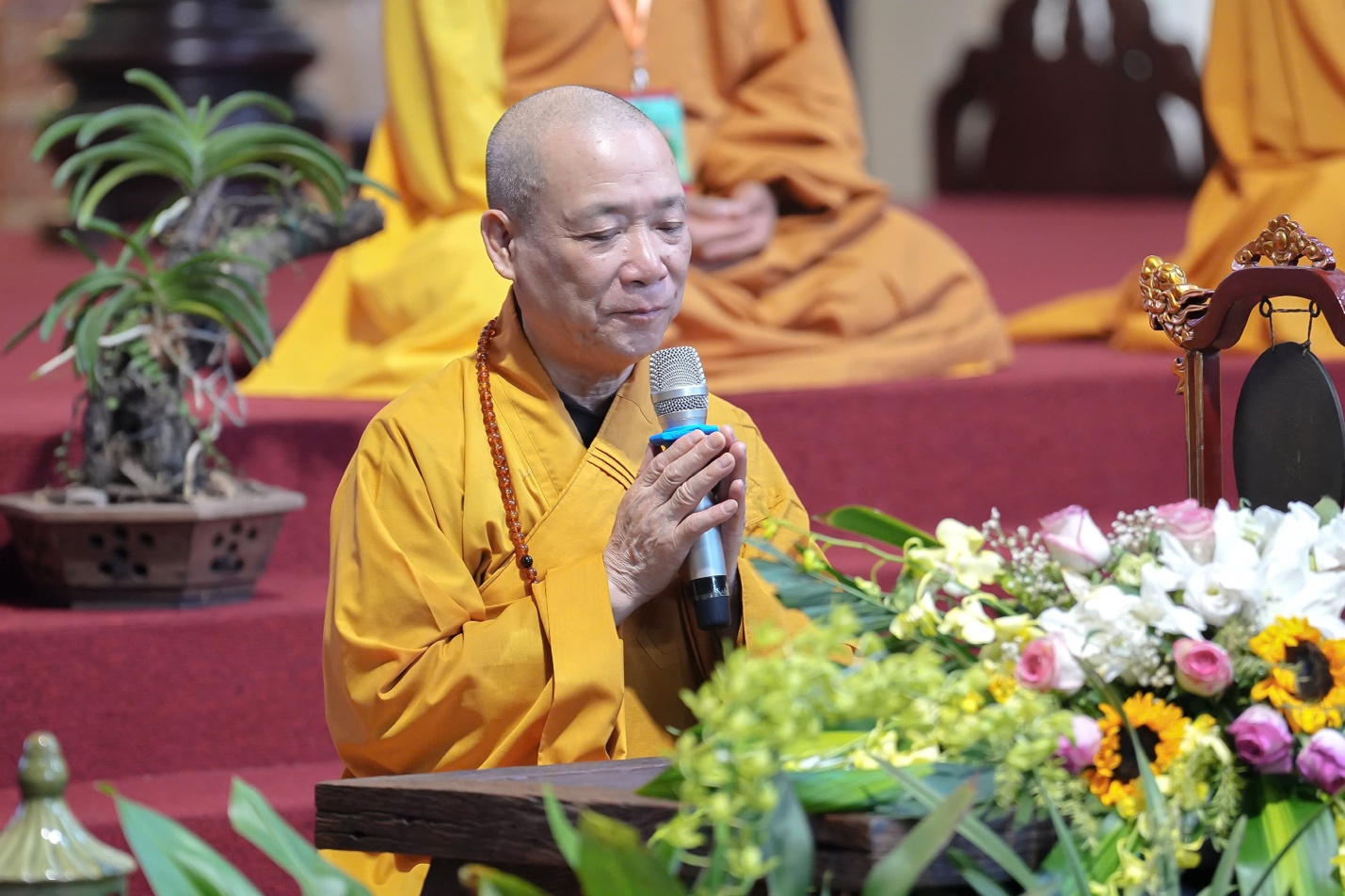 A person in a yellow robe holding a microphone AI-generated content may be incorrect.