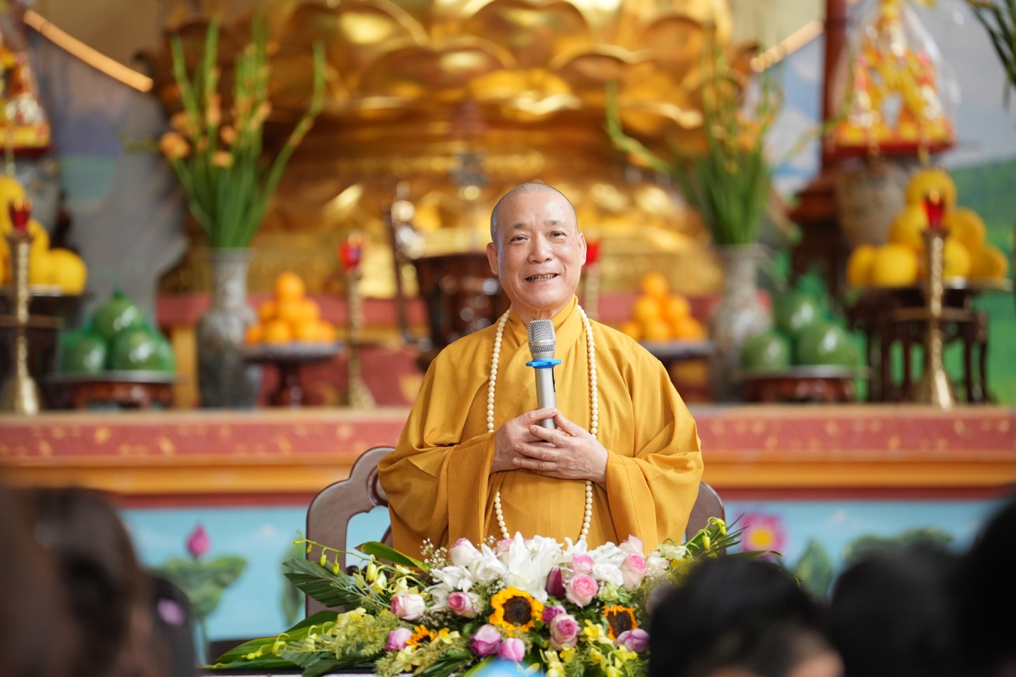 A person in a yellow robe holding a microphone AI-generated content may be incorrect.