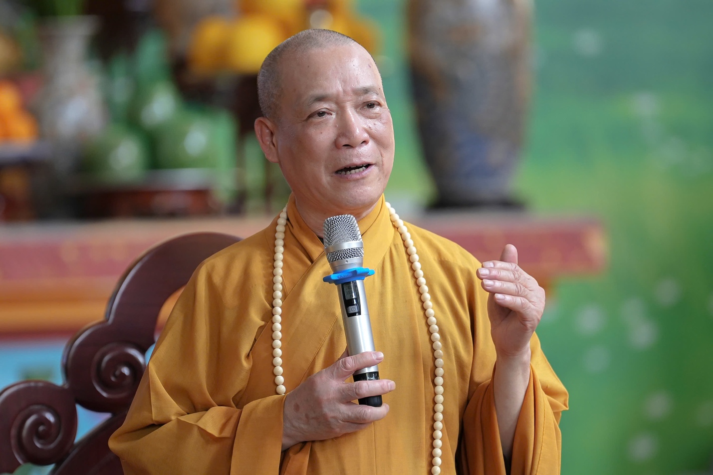 A person in a yellow robe holding a microphone AI-generated content may be incorrect.