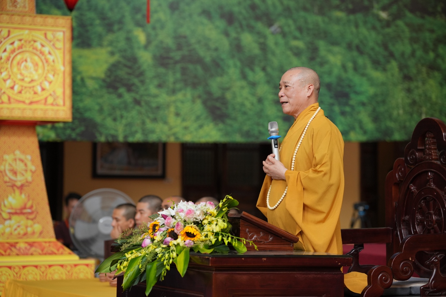 A person in a yellow robe holding a microphone AI-generated content may be incorrect.