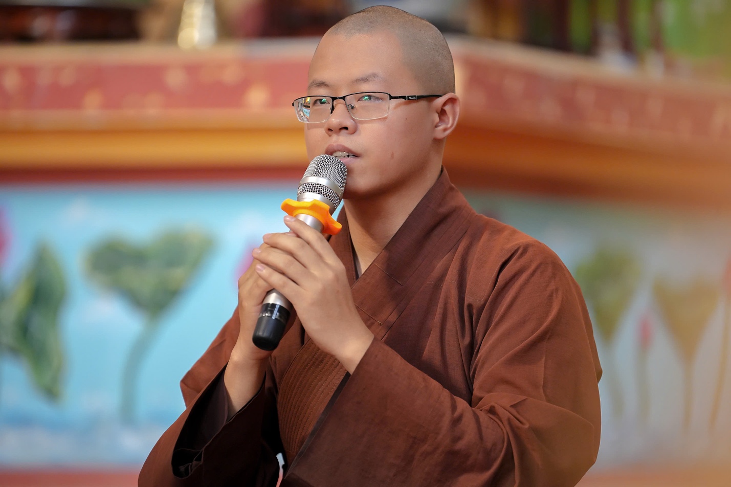 A person wearing glasses and a robe holding a microphone AI-generated content may be incorrect.